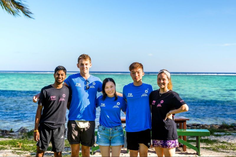 student volunteers standing together on a beach